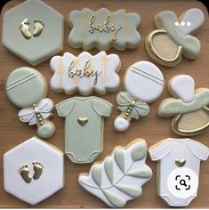 baby shower cookies are laid out on a wooden table with gold trimmings and white icing