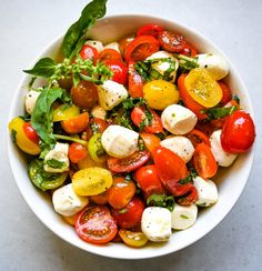 a white bowl filled with tomatoes, mozzarella and spinach on top of a table