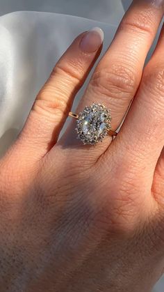 a woman's hand with a diamond ring on top of her finger and the other hand holding an engagement ring