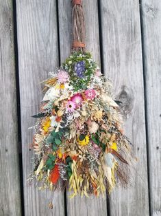 a bunch of dried flowers hanging from a wooden wall next to a wire hanger