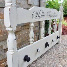 a white wooden bed frame with black knobs on it and the name hello sunshine painted on it