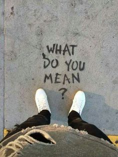 someone has written what do you mean? on the sidewalk with their feet in front of them