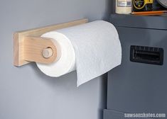 a roll of toilet paper is hanging on the wall next to a cabinet with drawers