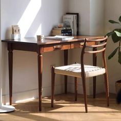 a desk with a chair next to it and a potted plant in the corner