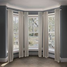 an empty room with three windows and two drapes on the window sill,