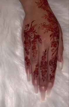 a woman's hand with red henna on top of white furnishing