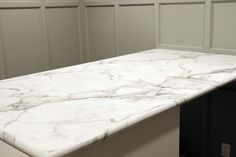 a white counter top in a kitchen with wood paneling on the wall behind it