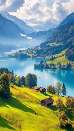 a scenic view of a lake surrounded by lush green grass and mountains in the background