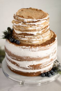 a layered cake with frosting and blueberries on top