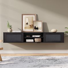 a black shelf with two pictures on it and some plants in front of the wall