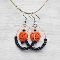 two orange jack - o'- lanterns are hanging from hoop earrings with black beads