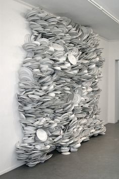 a large sculpture made out of books on the side of a wall in an empty room