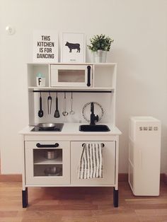 a white play kitchen with sink, stove and dishwasher