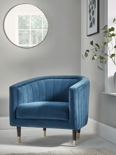 a blue chair sitting in front of a window next to a vase and potted plant