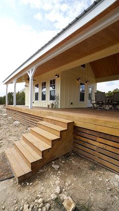 a house with wooden steps leading to the front door and covered patio area on top of it