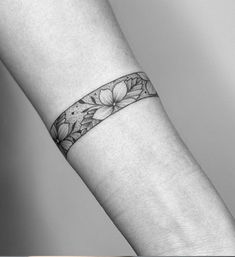 a woman's arm with a wristband and flower tattoo on the left forearm