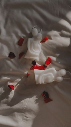 three pieces of plastic sitting on top of a white sheet covered in red and black confetti