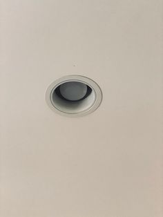 a white square light fixture with a black hole in the center on a gray wall