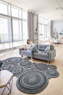 a woman sitting on top of a couch in a living room next to a window