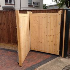 a wooden gate is open on a brick sidewalk