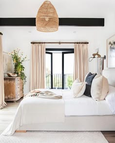 a bedroom with white bedding and curtains