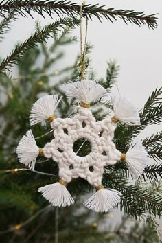 a crocheted snowflake ornament hanging from a pine tree