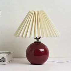 a red lamp sitting on top of a table next to a white box and plant