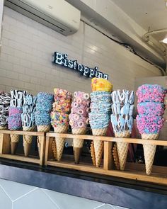 there are many ice cream cones on the counter at this store that have been decorated with colorful sprinkles