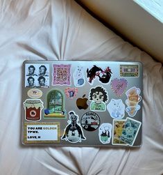 a laptop covered in stickers sitting on top of a bed