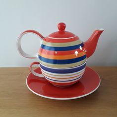 a red tea pot sitting on top of a saucer