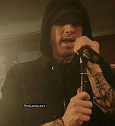 a man holding a microphone in his right hand and wearing a hoodie on the other