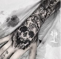 a person with a tattoo on their arm and hand holding a skull in the middle