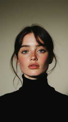 a woman with freckled hair and blue eyes wearing a black turtle neck sweater