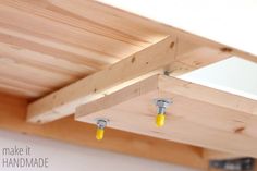 three yellow screws are attached to the ceiling in a room with white walls and wooden beams