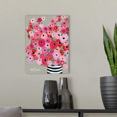 a vase filled with lots of pink flowers on top of a table next to a potted plant