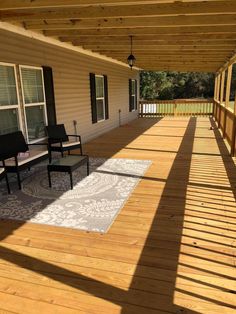 a porch with two chairs and a rug on the floor next to an awning