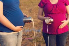 two pregnant women standing next to each other in a field with an electric device attached to their belly