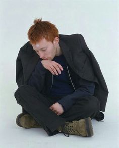 a young man sitting on the ground with his head in his hands