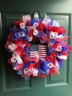 a patriotic wreath with an american flag on the front door and red white and blue mesh