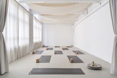 yoga mats are lined up on the floor in front of white walls and drapes