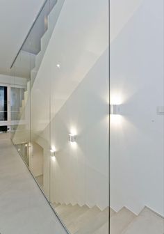 an empty room with some stairs and lights on the wall in front of glass doors