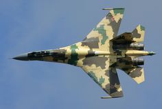 a camouflaged fighter jet flying through a blue sky