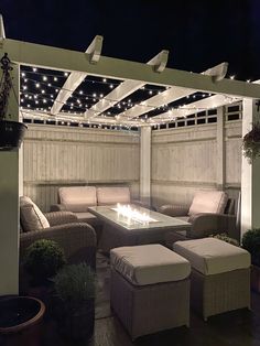 an outdoor living area with couches, tables and lights on the pergolan roof