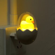 a yellow rubber ducky floating in an egg shell on a wall mounted light fixture