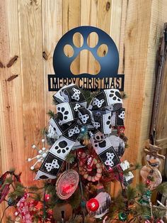 a decorated christmas tree in front of a wooden fence with a dog's paw on it