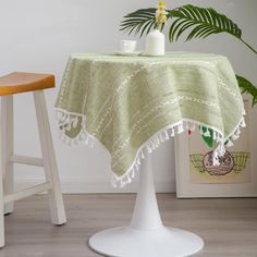 a table with a green table cloth on it next to a stool and potted plant