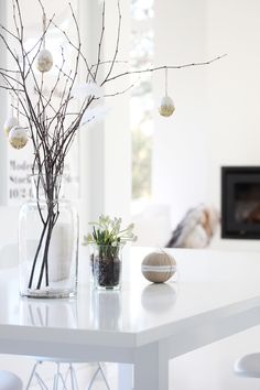 a white table topped with a vase filled with flowers and ornaments next to a fire place