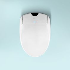 an overhead view of a white toilet with its lid up and the seat down, against a light blue background