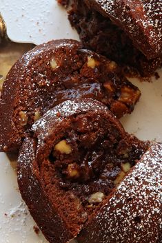 chocolate cake with nuts and powdered sugar on top, cut in half to show the inside