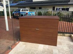 a large wooden box sitting on the side of a road next to a fence and building